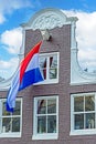 Dutch flag against a medieval facade from a house in Amsterdam the Netherlands at kings day Royalty Free Stock Photo