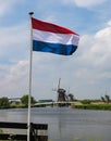 Quintessential Dutch photo with flag, canal and windmills Royalty Free Stock Photo