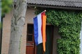 A dutch flag with an orange pennon in front of a house for kingsday in holland
