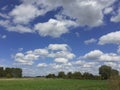 A dutch landscape with a blue sky with clouds above a green meadow Royalty Free Stock Photo