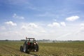 Dutch landscape with field of overblown bulbs, tractor, irrigation, blue sky, clouds, rural environmentfiled