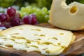 Dutch Maasdam hard cheese with holes, piece and sliced, served outdoor in green garden Royalty Free Stock Photo