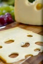 Dutch Maasdam hard cheese with holes, piece and sliced, served outdoor in green garden Royalty Free Stock Photo