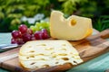 Dutch Maasdam hard cheese with holes, piece and sliced, served outdoor in green garden Royalty Free Stock Photo