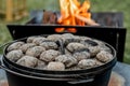 Dutch oven camp cooking with coal briquettes beads on top. Campfire Royalty Free Stock Photo