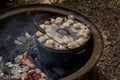 Dutch oven camp cooking with coal briquettes beads on top. Campfire in a firepit. Camping cooking Royalty Free Stock Photo