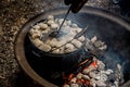 Dutch oven camp cooking with coal briquettes beads on top. Campfire in a firepit. Camping cooking Royalty Free Stock Photo