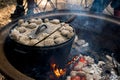 Dutch oven camp cooking with coal briquettes beads on top. Campfire in a firepit. Camping cooking Royalty Free Stock Photo