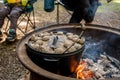 Dutch oven camp cooking with coal briquettes beads on top. Campfire in a firepit. Camping cooking Royalty Free Stock Photo
