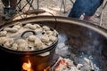 Dutch oven camp cooking with coal briquettes beads on top. Campfire in a firepit. Camping cooking Royalty Free Stock Photo