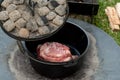 Dutch oven camp cooking with coal briquettes beads on top, Meat lamb shoudler in the camp oven Royalty Free Stock Photo