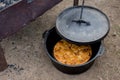 Dutch oven campfire cooking - baking an apple pie in cast iron camp oven Royalty Free Stock Photo