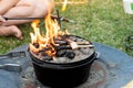 Dutch oven campfire cooking with coal briquettes and flame on top, Camping life Royalty Free Stock Photo