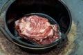 Dutch oven campfire cooking meat. Raw lamb shoulder in the camp oven Royalty Free Stock Photo