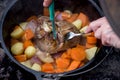 Dutch oven campfire cooking process - lamb and vegetables in a cast iron camp oven Royalty Free Stock Photo