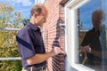 Dutch painter paints window frame with brush