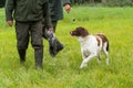 A Dutch partridge dog, Drentse patrijs hond, walking on a leash with two hunters holding a pigeon Royalty Free Stock Photo