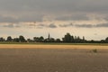 Plowed farmland in the dutch countryside and a little village in the background at a summer evening