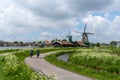 Dutch senior citizens enjoy a bicycle ride along the canals of North Holland with traditional windmills in the background