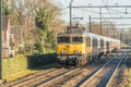 Dutch train locomotive with germand wagons passing the village during wintertime Royalty Free Stock Photo