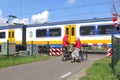 Senior couple waits while a Dutch sprinter train is passing at the railway crossing, Netherlands