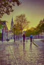 Dutch Travel Ideas. Friendly Couple in Holland Traveling on Bicycles in Old City Delft During Pouring Rain with Grey Clouds