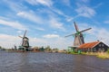 Dutch typical landscape. Traditional old dutch windmill with house and blue sky near river in the Zaanse Schans village, Netherlan Royalty Free Stock Photo