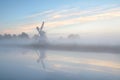 Dutch windmill in dense fog during sunrise Royalty Free Stock Photo