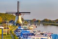 Dutch Windmill In Front of The Canal With Moored Motorboats at Marina Located in Traditional Village in Holland, The Netherlands. Royalty Free Stock Photo