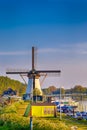 Dutch Windmill In Front of The Canal With Moored Motorboats at Marina Located in Traditional Village in Holland, The Netherlands. Royalty Free Stock Photo