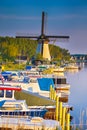 Dutch Windmill In Front of The Canal With Moored Motorboats at Marina Located in Traditional Village in The Netherlands. Shot at Royalty Free Stock Photo