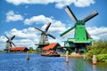 Dutch windmill in green countryside close to Amsterdam, Netherlands, with blue sky and river water