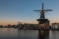 Dutch windmill, in the town of Haarlem, at sunset. The water is smooth, due to a long shutter speed Royalty Free Stock Photo