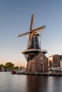 Dutch windmill, in the town of Haarlem, at sunset. The water is smooth, due to a long shutter speed Royalty Free Stock Photo