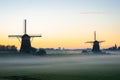 Dutch windmills on an early autumn morning with low fog over the fields Royalty Free Stock Photo