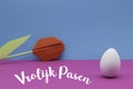Dutch words Vrolijk Pasen Happy Easter with a white egg and a red tulip Royalty Free Stock Photo