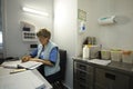 On duty. Nurse sitting at a nurseÃ¢â¬â¢s station and writing in a paper Royalty Free Stock Photo