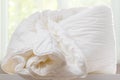 A duvet lies on a chest of drawers against a blurred window Royalty Free Stock Photo