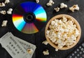 DVD or blu ray movie disc with tv remote control, movie tickets and bowl of popcorn on dark background. Home theatre movie or
