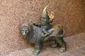 Dwarf riding a lion sleeping cap sitting on a lion and waving hello. Small bronze figures of gnomes on the streets of