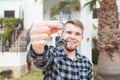 Dwelling, buying home, real estate and ownership concept - handsome man showing his key to new home Royalty Free Stock Photo