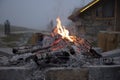 The dying fir.Thick smoke over the fire, in the background the stone wall of the house and the fog