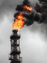 Dying Flame at Deserted Refinery Flare Stack With Dark Smoke Trails Under Overcast Sky Indicating Decline in Industrial Royalty Free Stock Photo