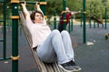 Elderly woman doing exercises in sports bars on outdoor sports ground