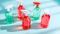 dynamic array of red and green plastic spray bottles with white triggers rests on a light blue surface, ready for cleaning tasks Royalty Free Stock Photo