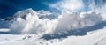 Dynamic avalanche activity cutting through a tranquil snow-covered mountainscape under the vast blue.