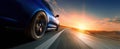 The dynamic blue car speeding along a scenic road at sunset. AI generated image Royalty Free Stock Photo
