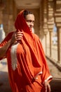 Dynamic fashion portrait of a beautiful young adult woman in Arabian attire and head covered in a shawl, looking aside