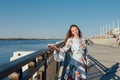 Dynamic fashion style Portrait of a young beautiful girl walking along the waterfront of the city