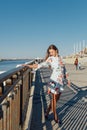 Dynamic fashion style Portrait of a young beautiful girl walking along the waterfront of the city